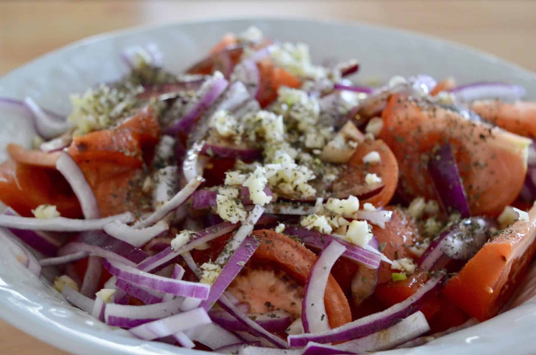 tomatoes, red onions, garlic, balsamic, olive oil, and oregano in a bowl. 