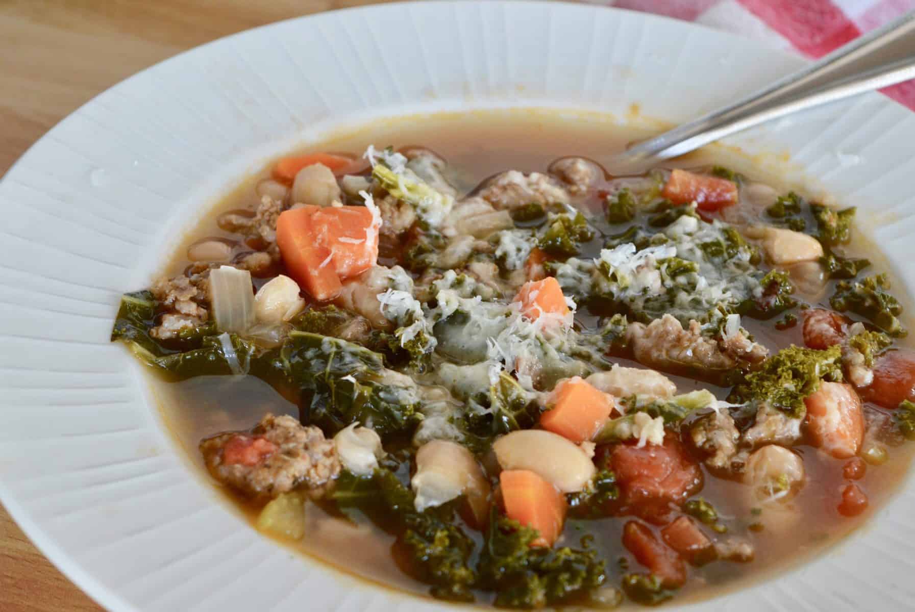 close up photo of soup in a white bowl with parmesan cheese sprinkled on top. 