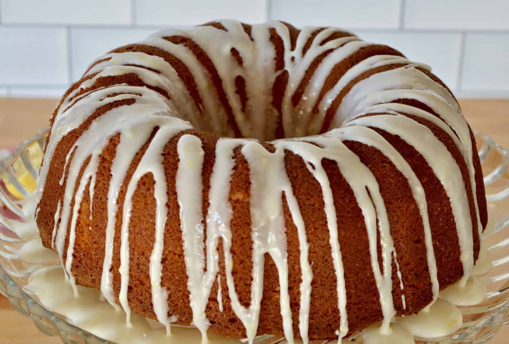 olive oil bundt cake on a glass pedestal with honey lemon drizzle. 