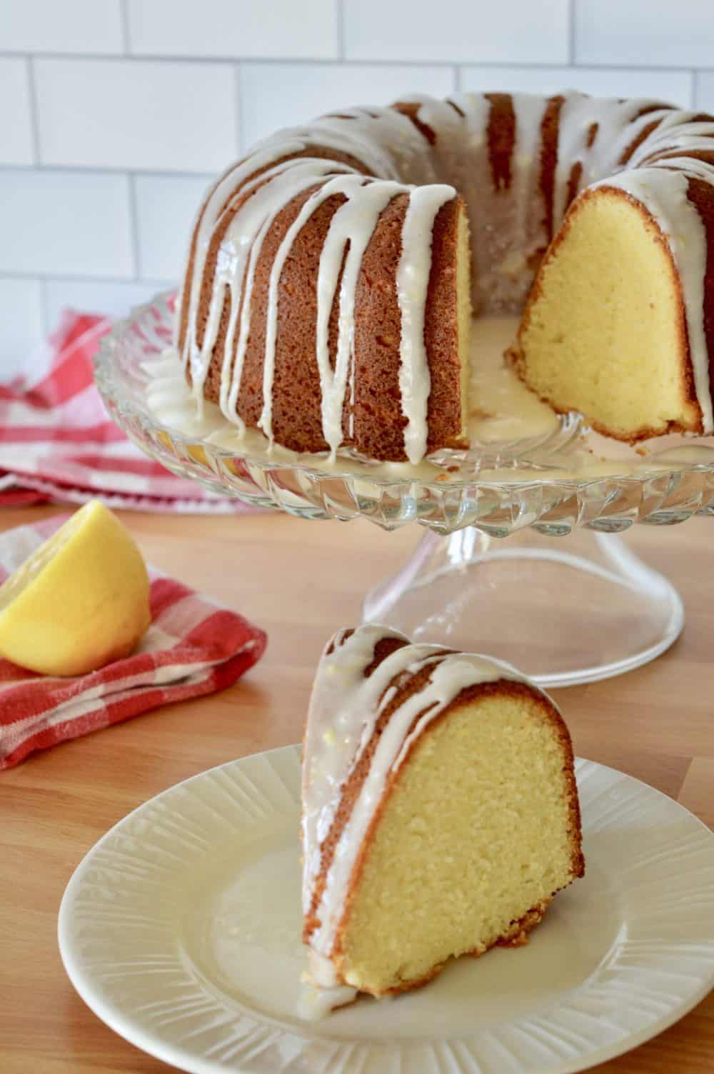 olive oil yogurt bundt cake on a pedestal with a checkered napkin in the background. 
