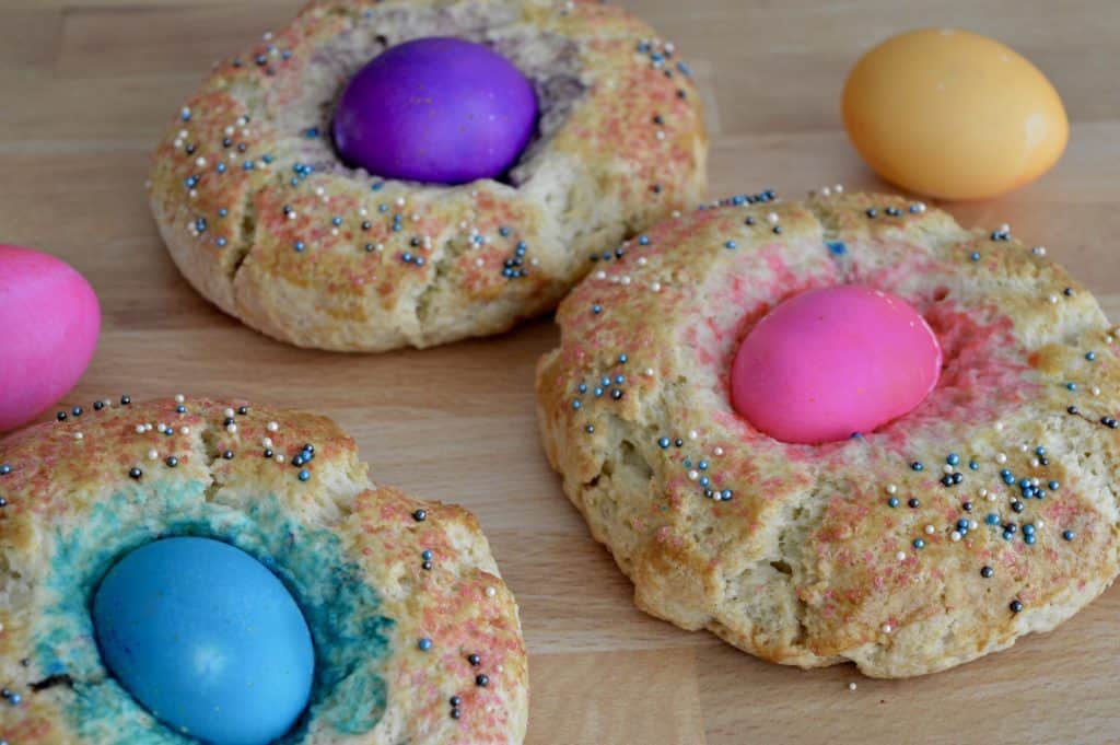 Italian Easter Bread on a wood surface with colored eggs.