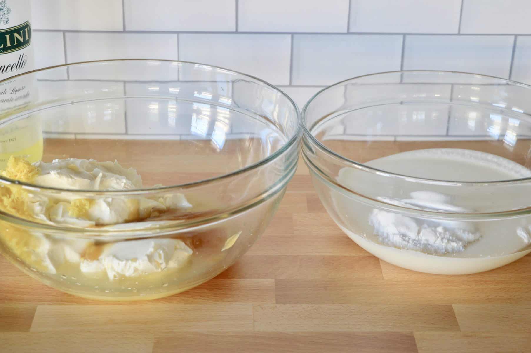 two glass bowls on a wood counter with filling for the limoncello tiramisu. 