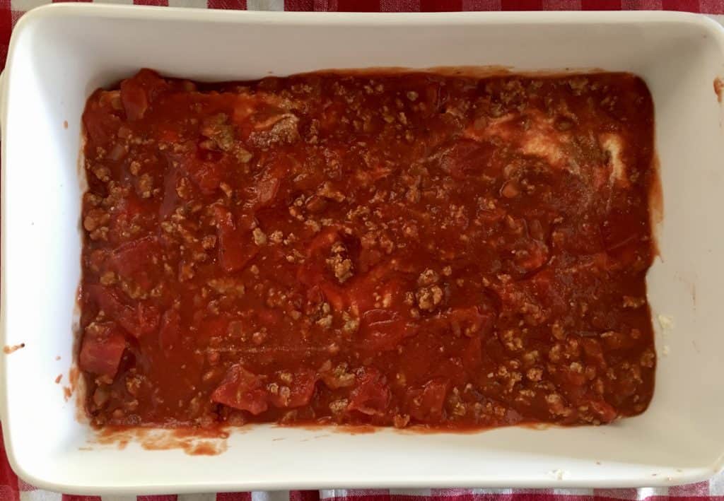 turkey meat sauce spread over the bottom of a baking dish.