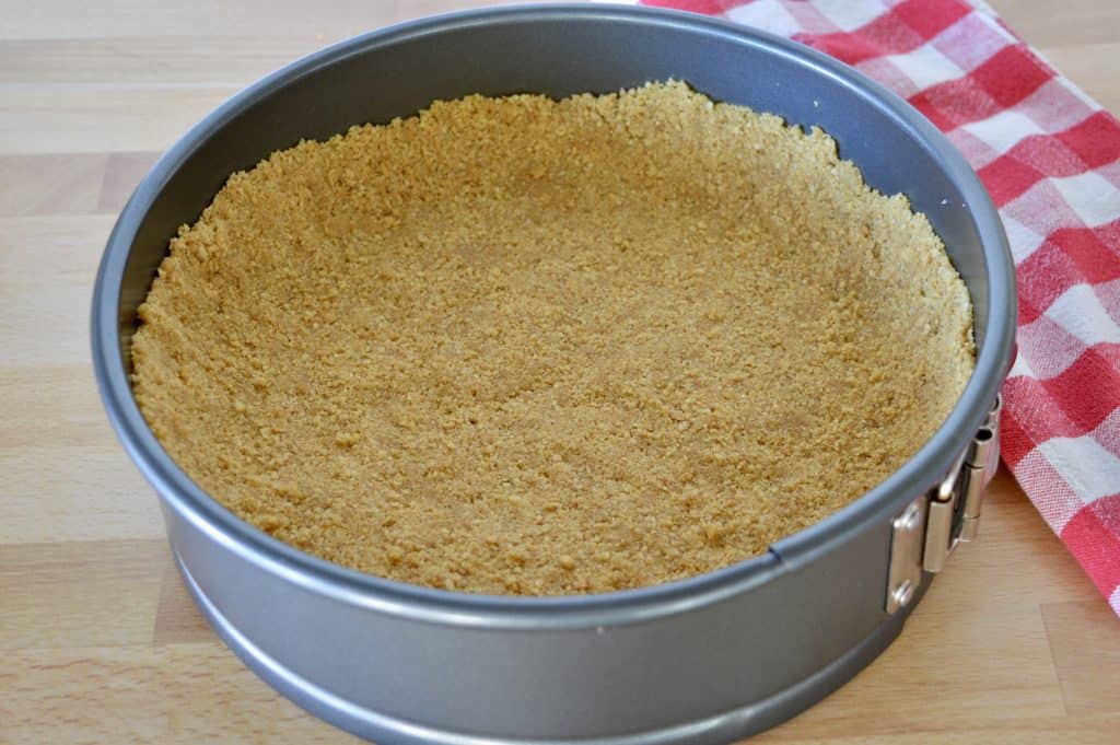 Graham cracker crumbs pressed into the bottom of a springform pan.