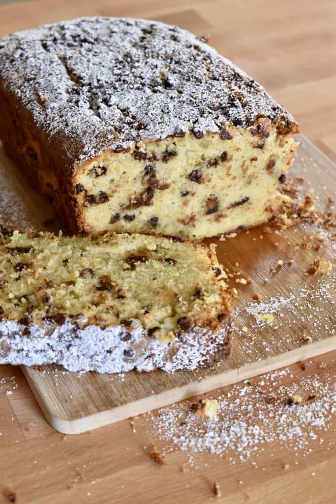 Cannoli Pound Cake on a wood cutting board with powdered sugar dusted on top.