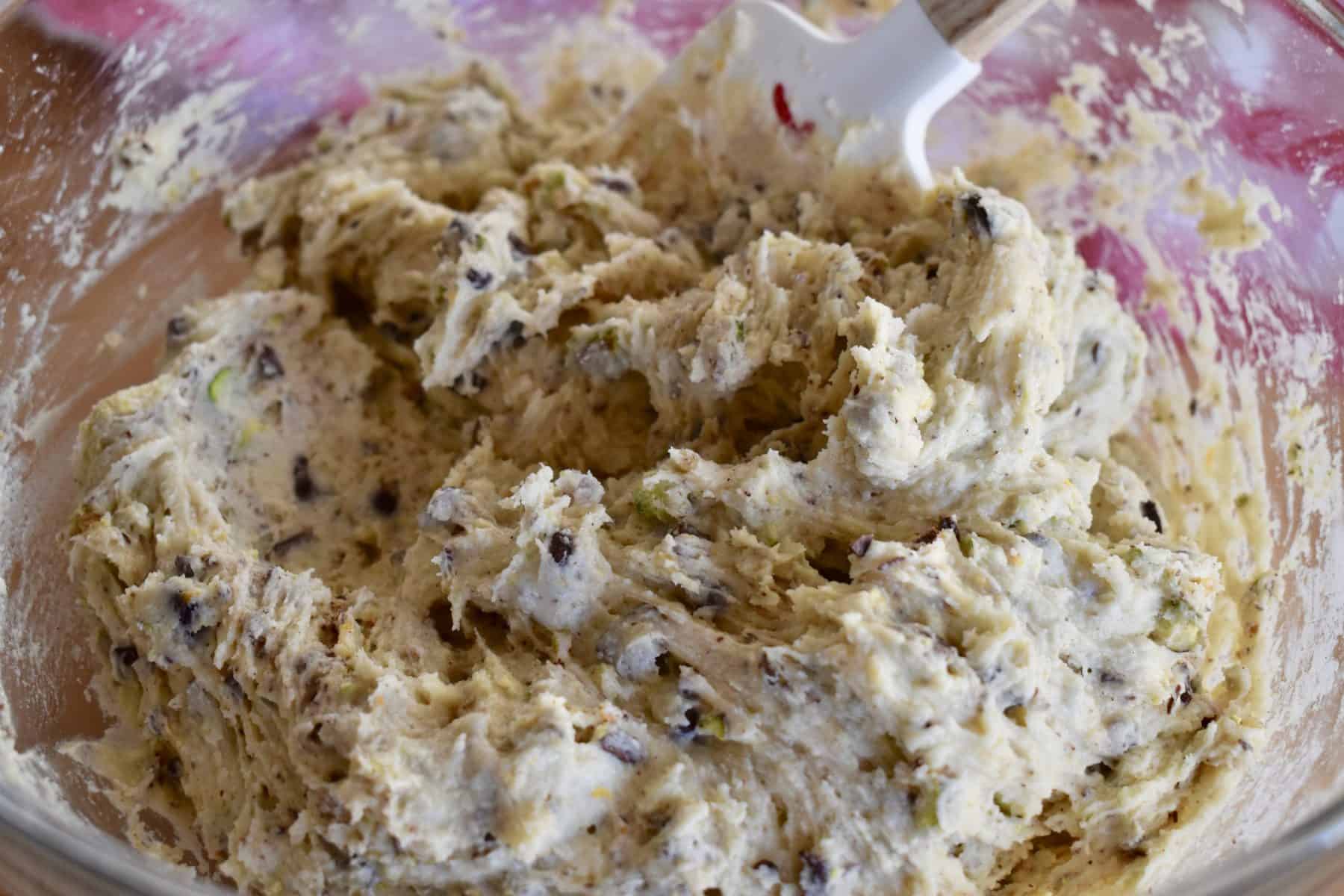 close up of batter with pistachios and chocolate chunks showing. 