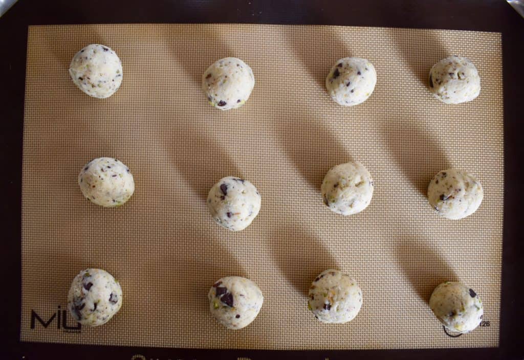 Pâte roulée en boules sur un tapis de cuisson antiadhésif. 