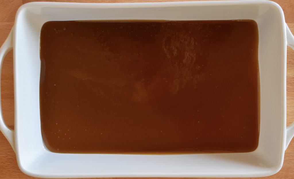 brown sugar butter mixture on the bottom of a white casserole dish.
