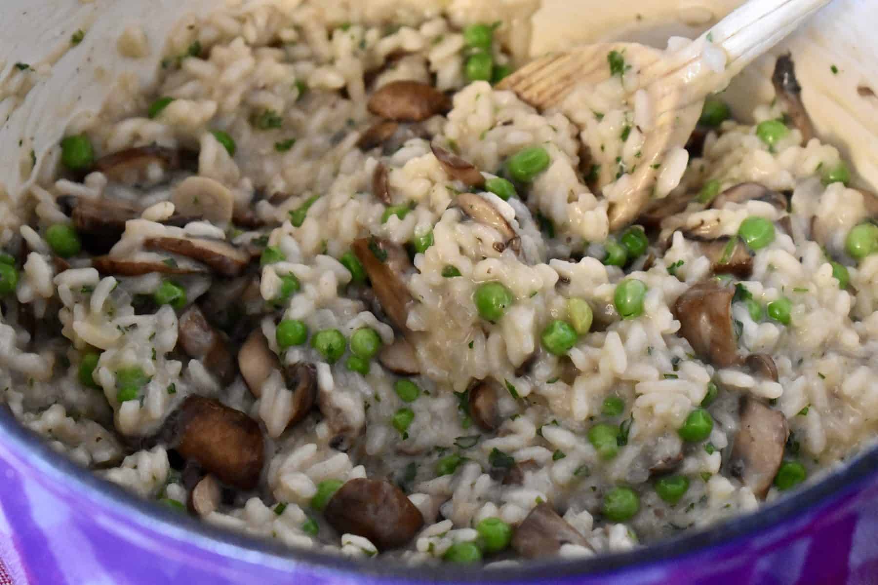 Finished Mushroom Pea Risotto in the cooking pot with a wooden spoon. 