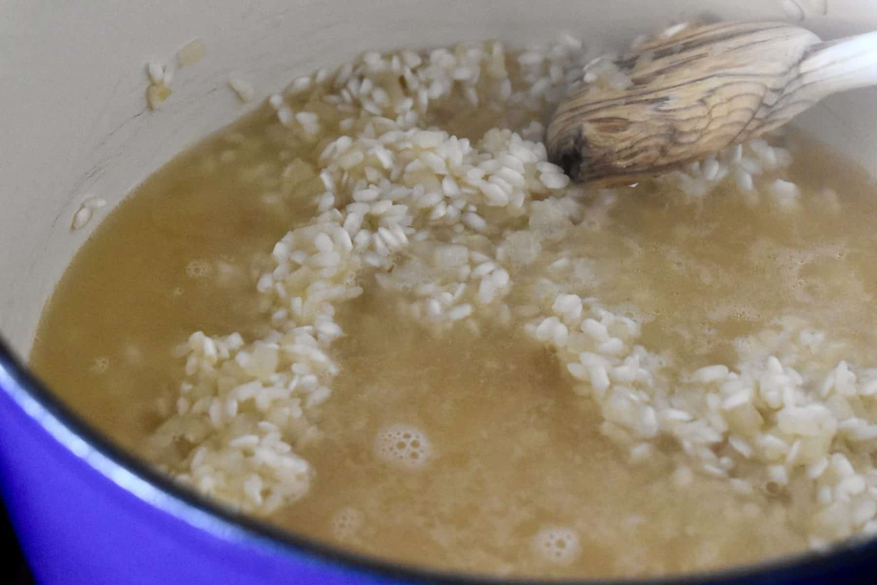 hot broth added to the arborio rice in a pot.