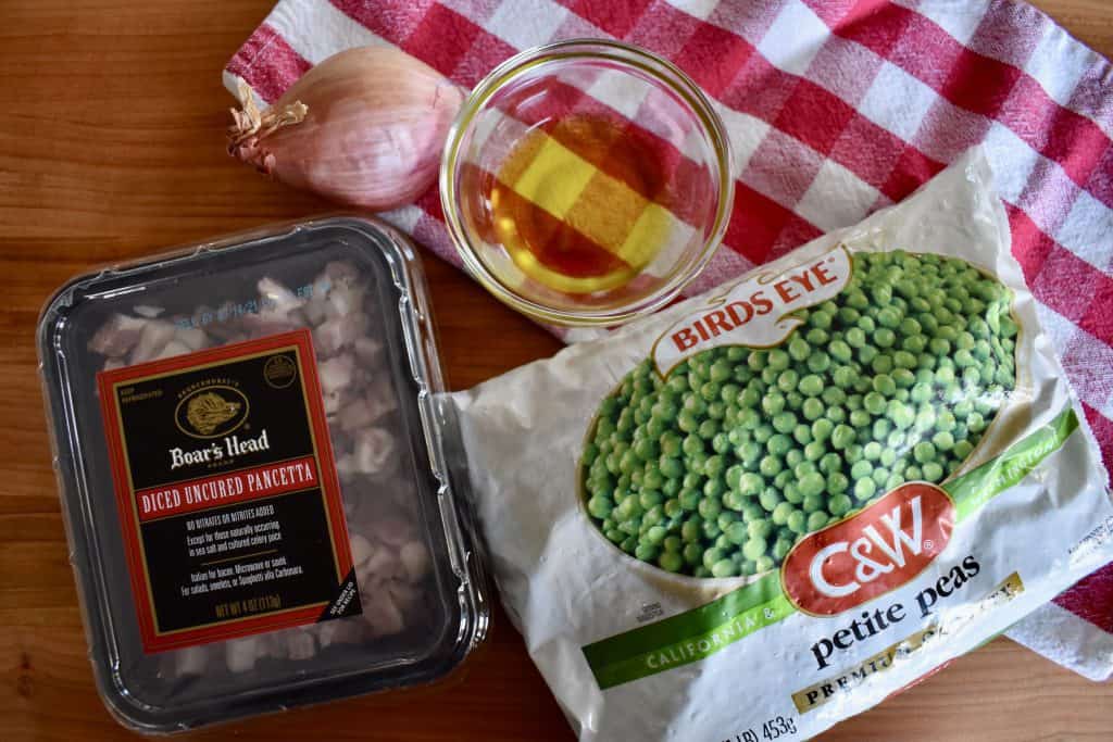 bag of frozen peas, diced pancetta, olive oil, and shallot on a checkered napkin.