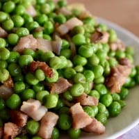 Peas and Pancetta piled high on a white plate.