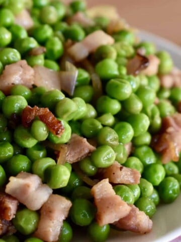 Peas and Pancetta piled high on a white plate.