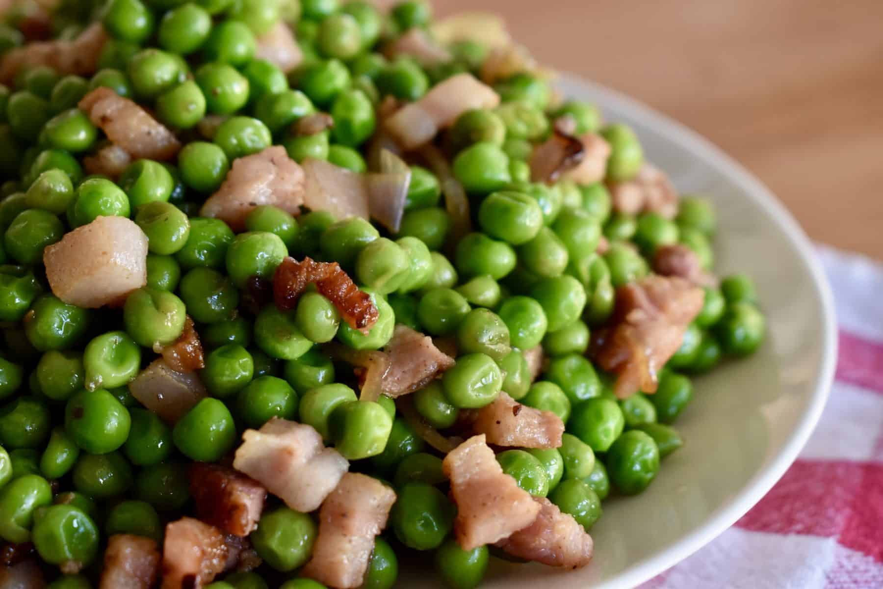 Peas and Pancetta piled high on a white plate.