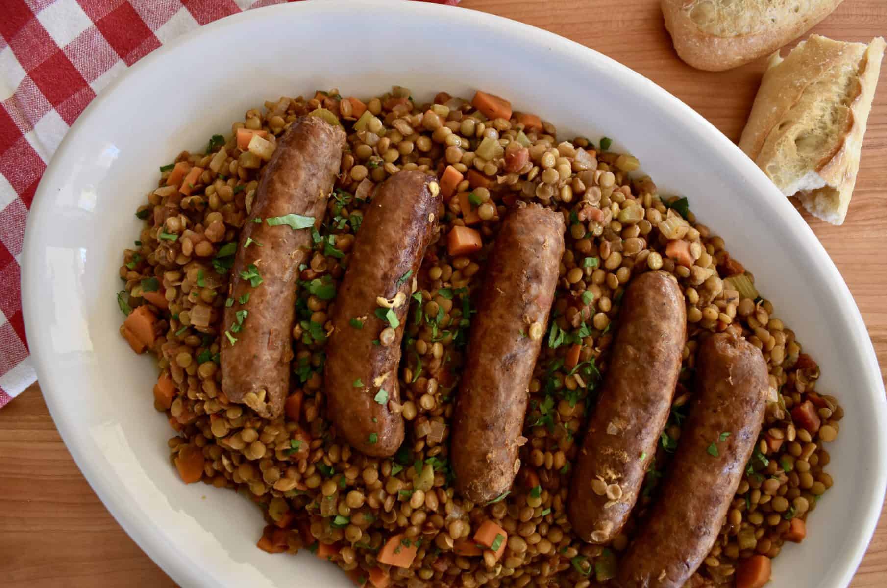 overhead photo of a platter of lentils with Italian sausage on top. 