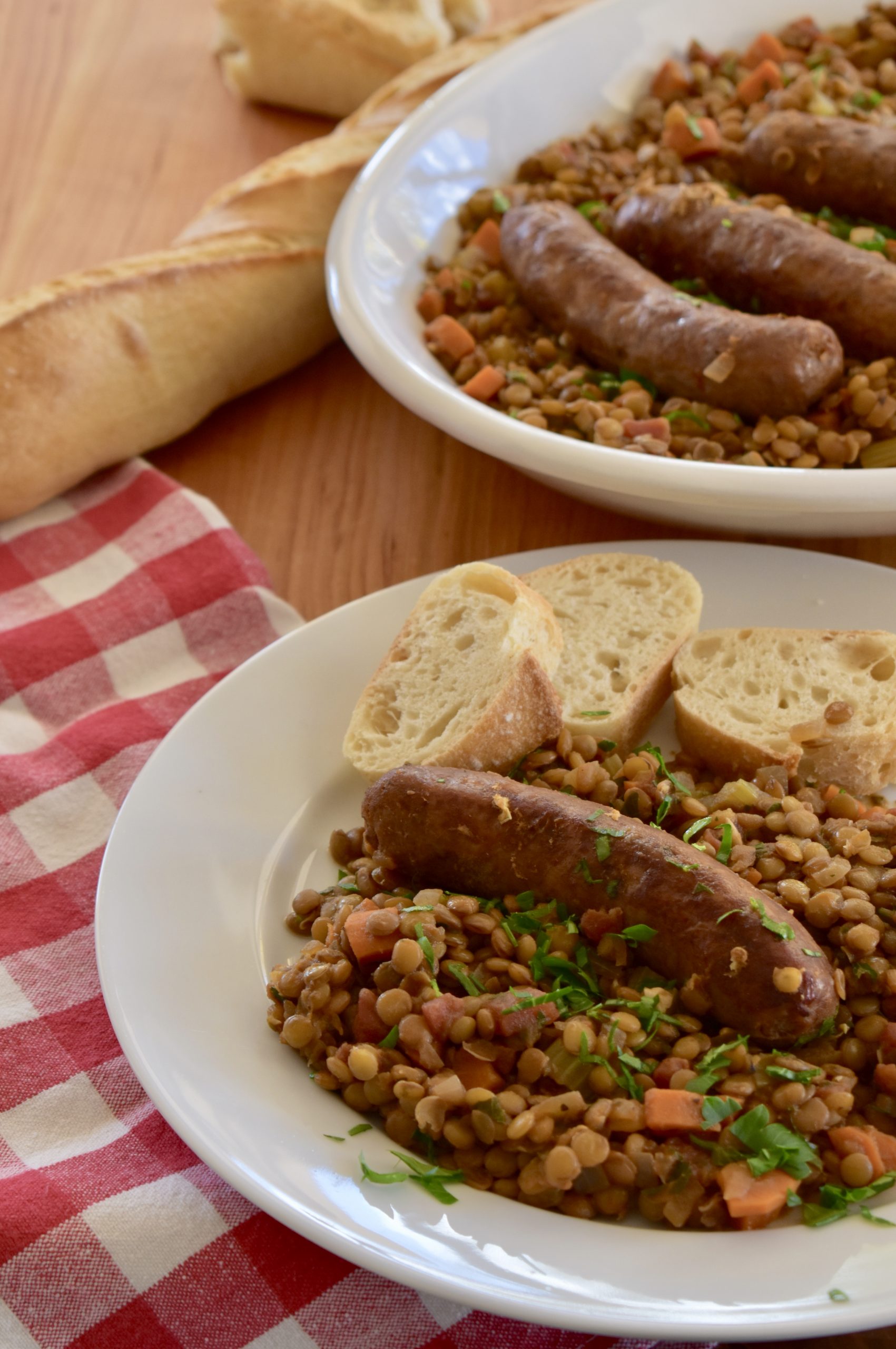 Italian Sausage and Lentils on a white serving platter with bread. 