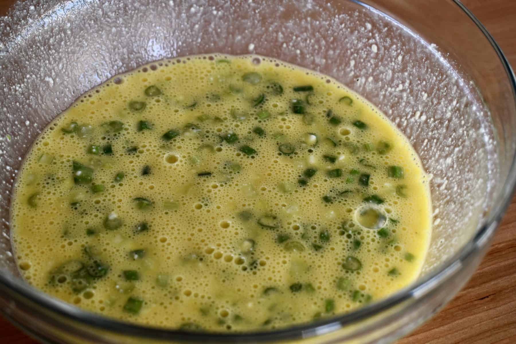 eggs whisked together in glass mixing bowl.