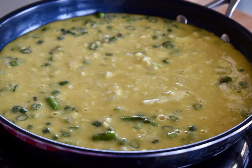 eggs poured over the veggies in the pan.