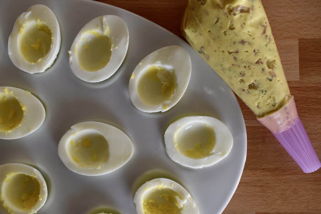 Hollowed out egg whites with a piping bag of filling next to it.