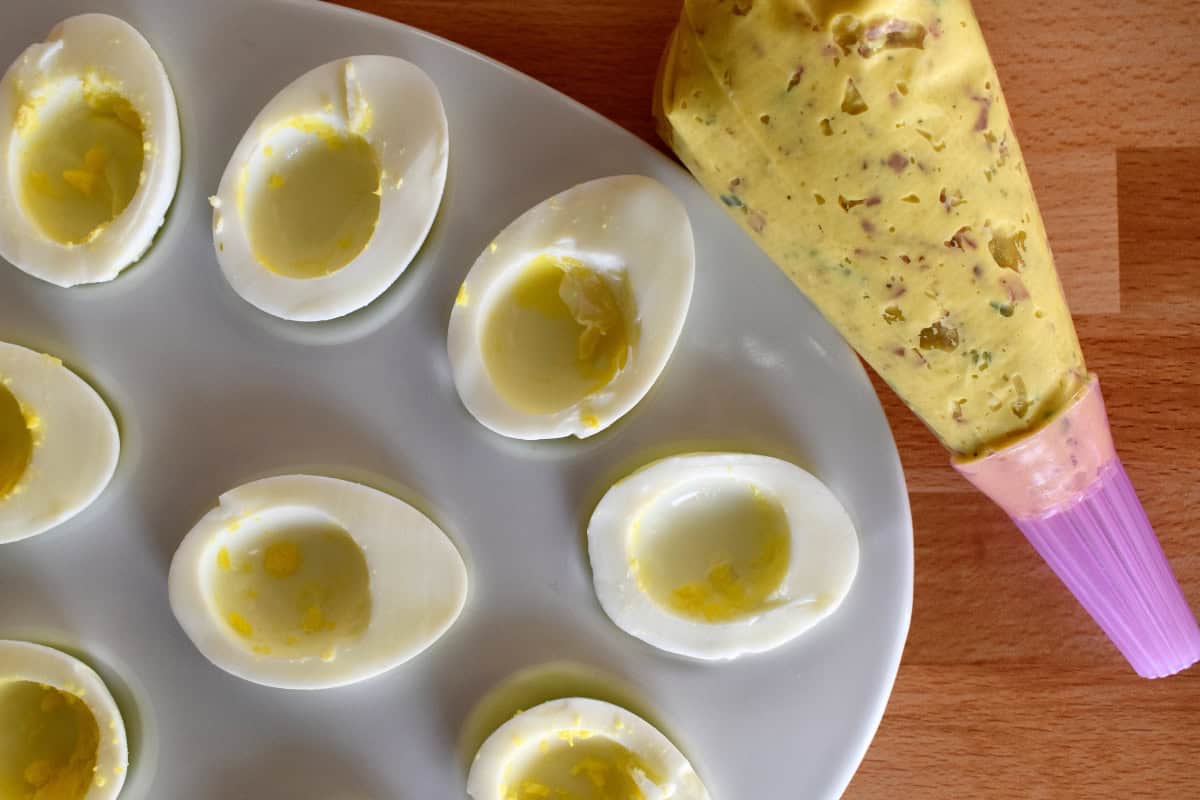 Hollowed out egg whites with a piping bag of filling next to it. 