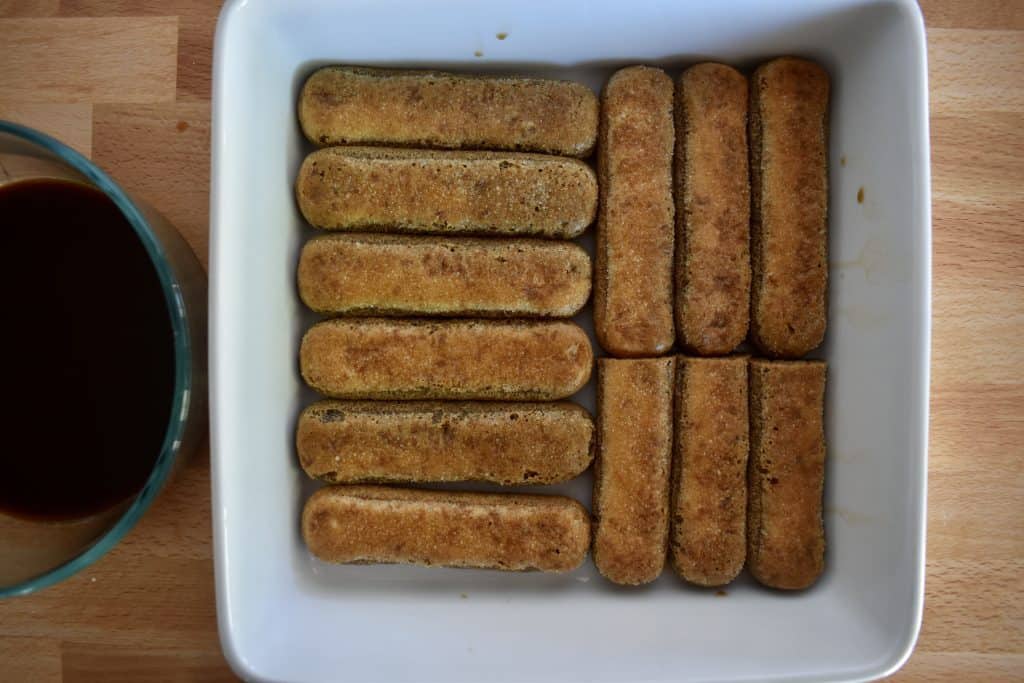 ladyfingers dipped in espresso kahlua mixture and placed in the bottom of a white baking dish.