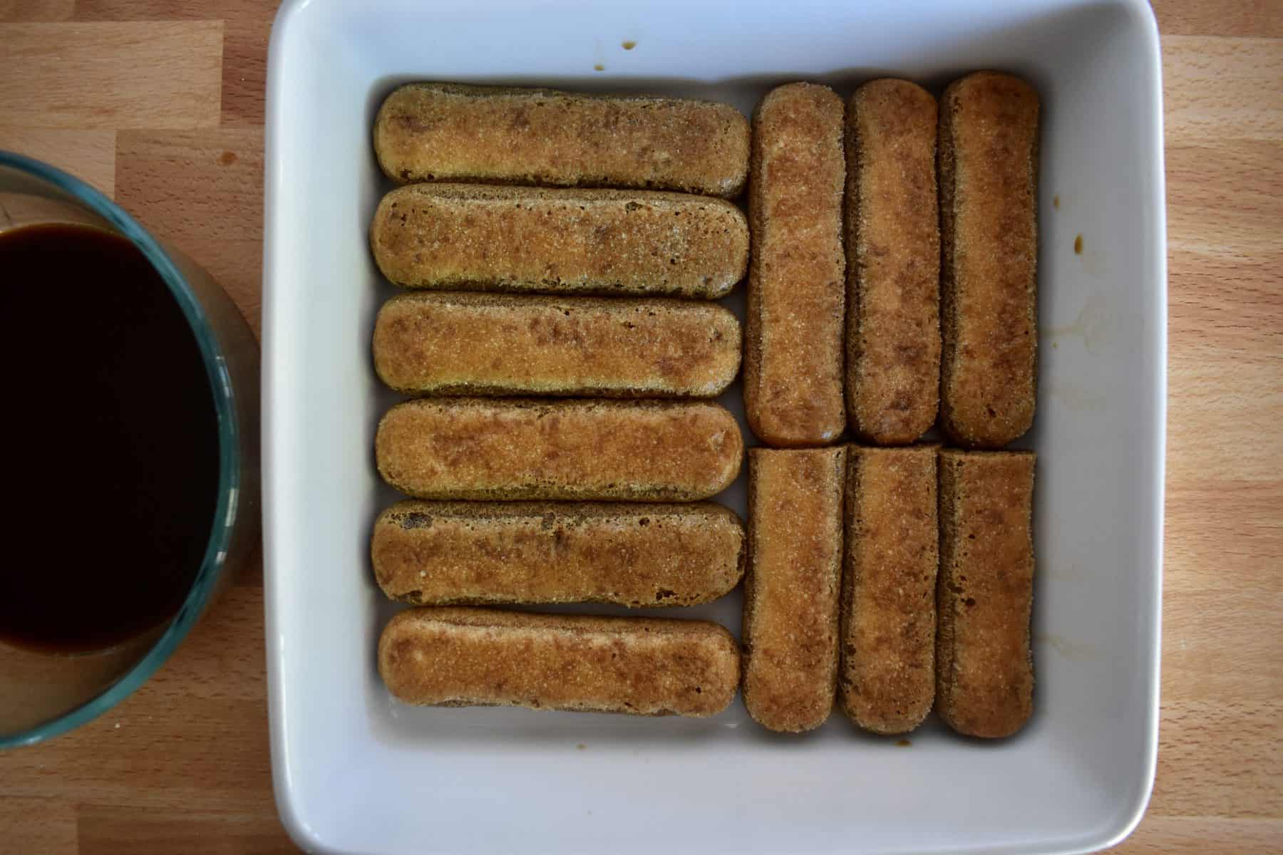 ladyfingers dipped in espresso kahlua mixture and placed in the bottom of a white baking dish. 