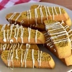 Pumpkin Biscotti with white chocolate drizzle stacked on a plate.