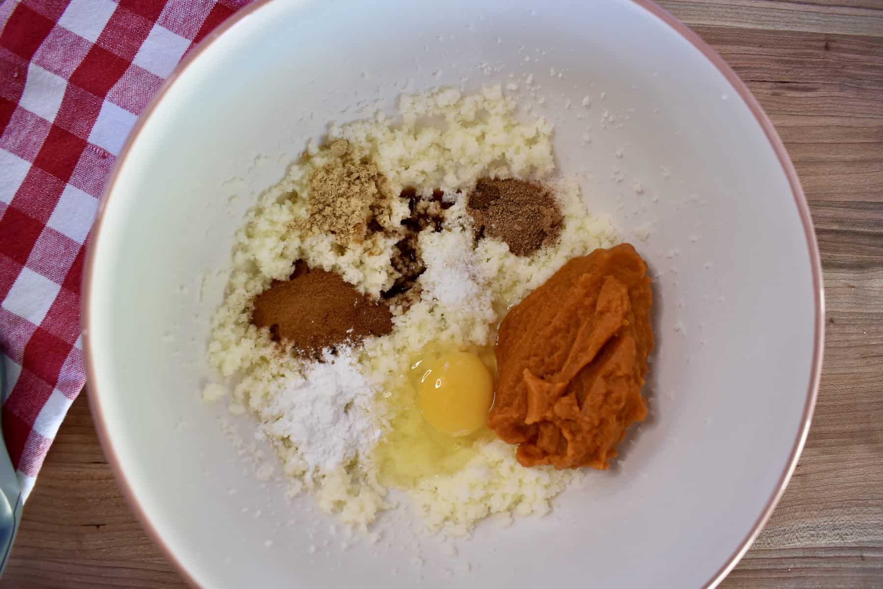 overhead photo of butter, sugar, spices, and puree in a white mixing bowl.