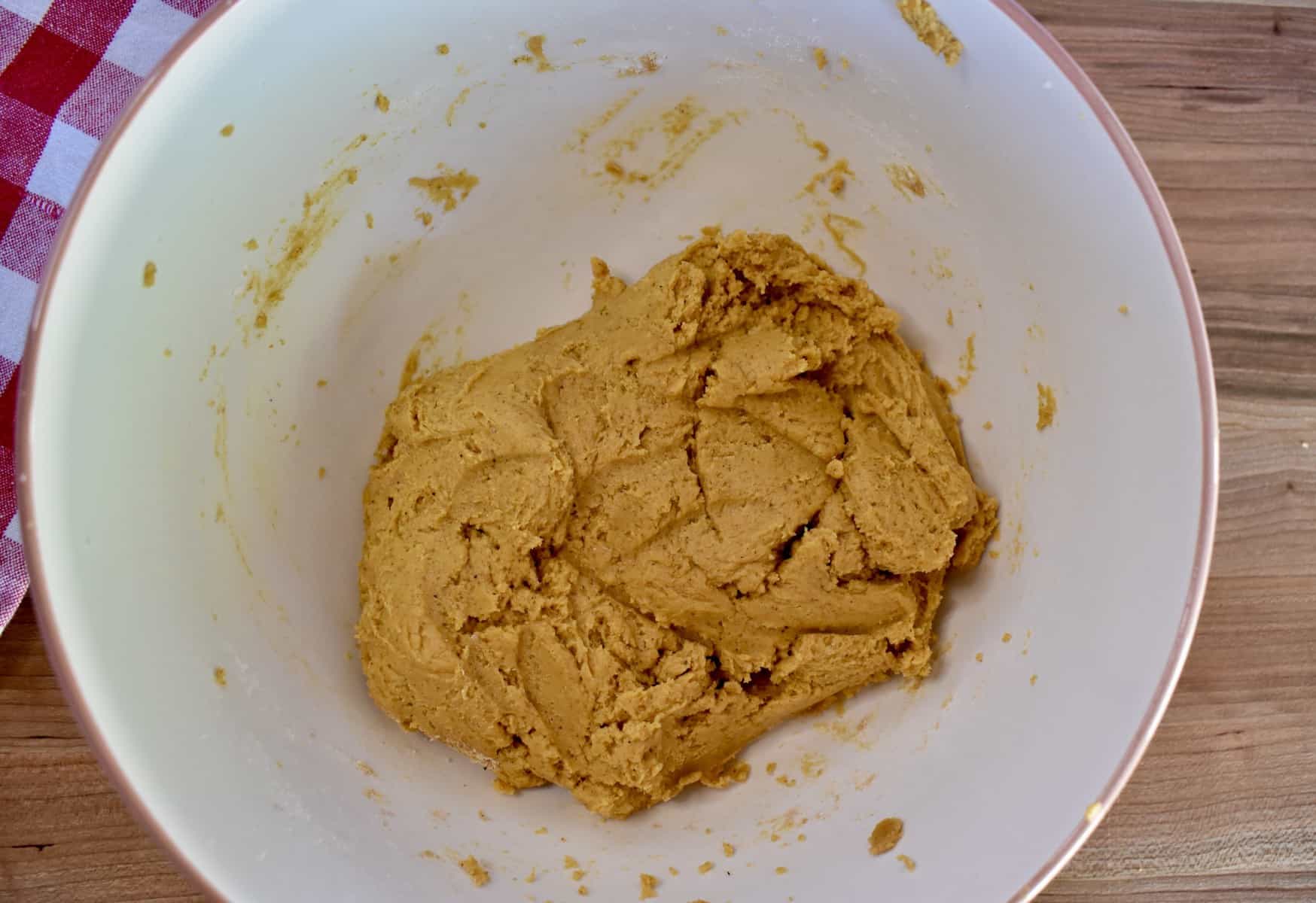overhead photo of pumpkin biscotti dough in a white mixing bowl. 
