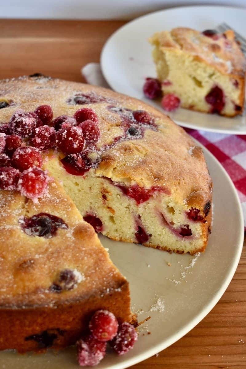 Vertical image of cranberry ricotta cake on a plate. 