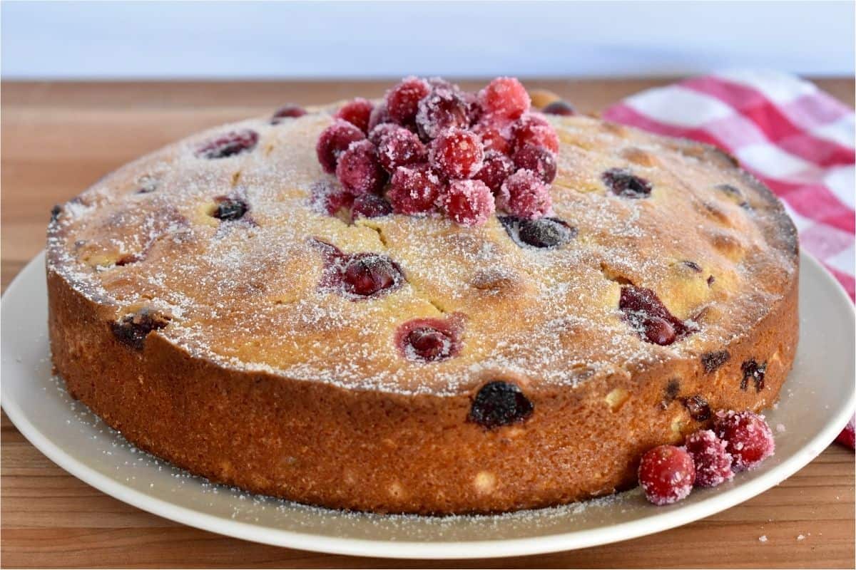 Cranberry Ricotta cake on a plate with sugared cranberries on top. 