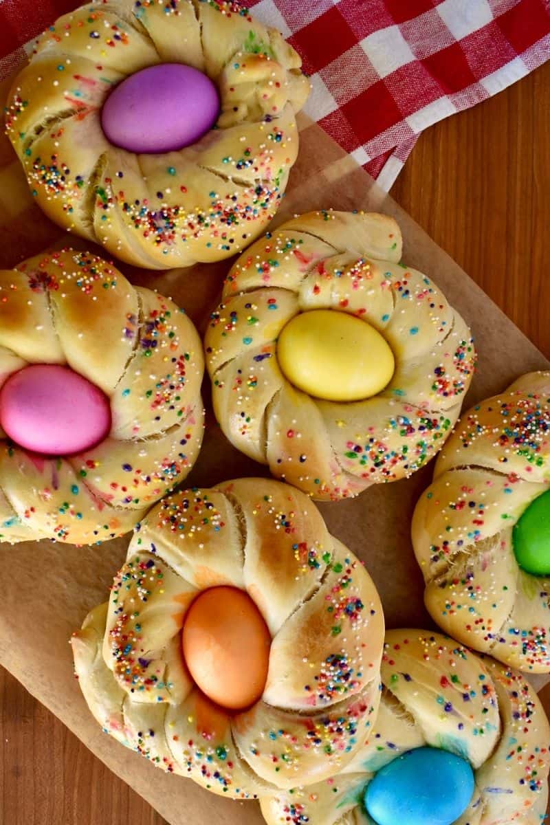 Italian Easter Bread rings on a counter with dyed eggs and sprinkles. 