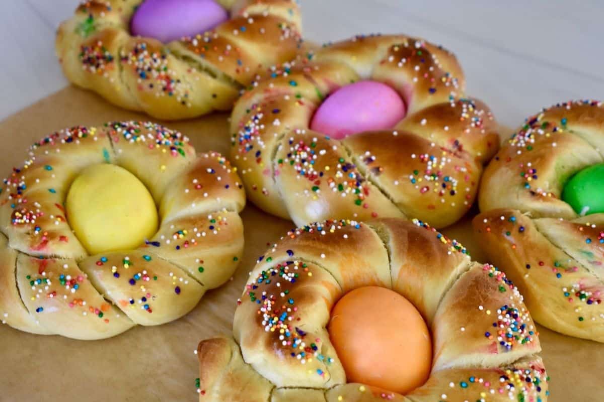 Pane di Pasqua with dyed eggs and sprinkles on a white countertop. 