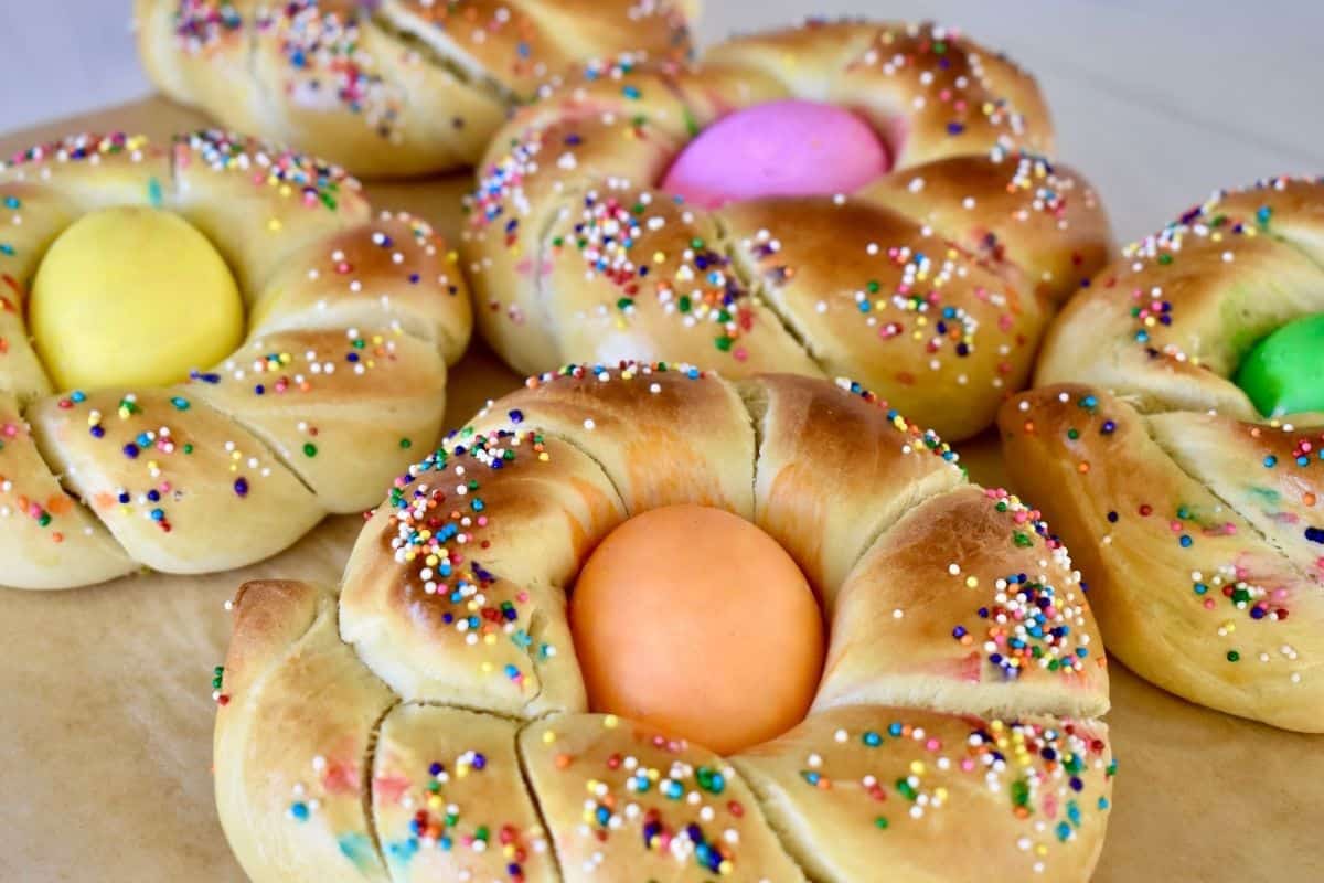 Italian Easter Bread, Pane di Pasqua, Rings with dyed eggs and sprinkles on a white countertop. 