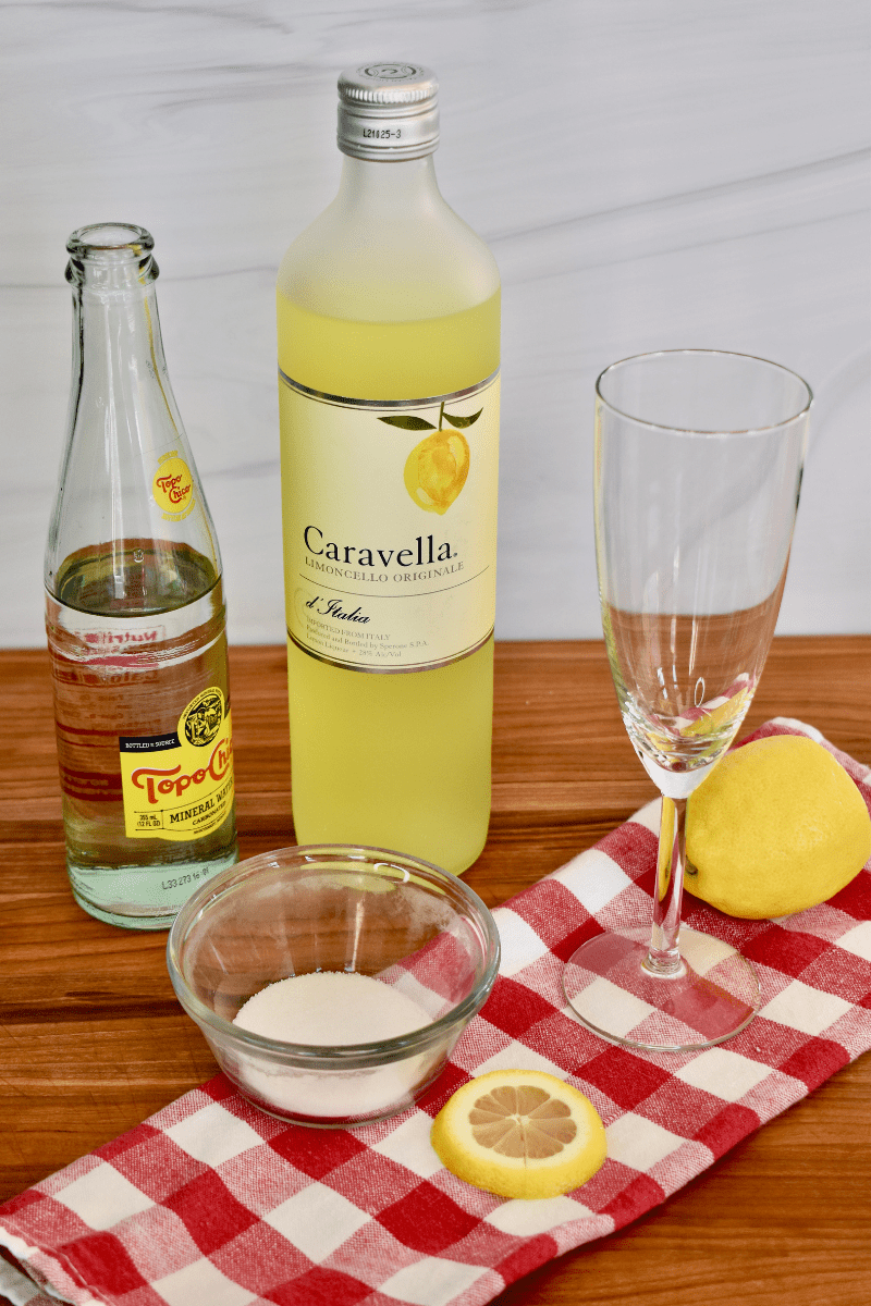 ingredients needed to make the cocktail on a wood cutting board with a checkered napkin. 