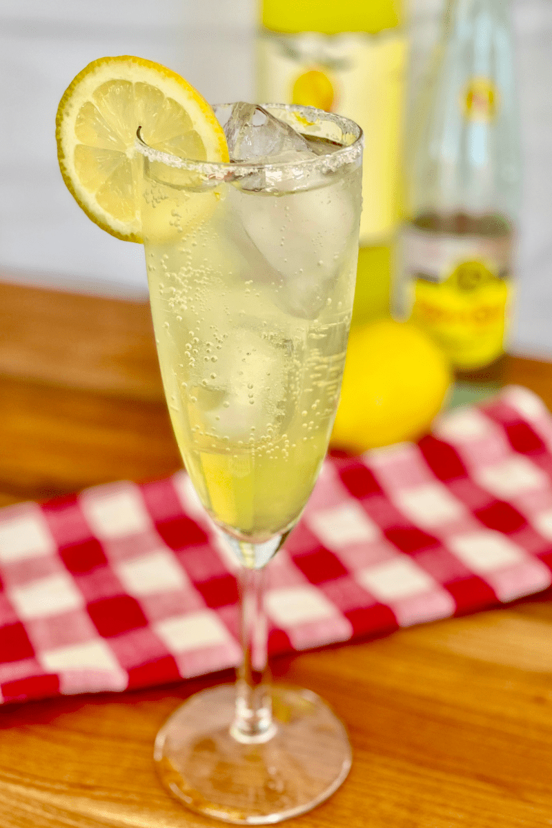 Limoncello Spritz on a counter with limoncello and sparkling water in the background. 