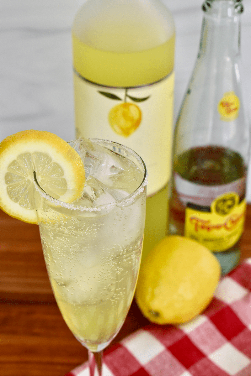 Limoncell Spritz in a champagne glass with ingredients behind it. 