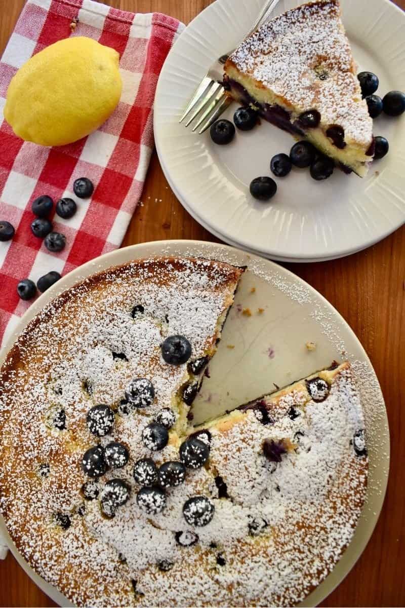 Overhead photo of blueberry ricotta cake with lemon and blueberries next to it. 