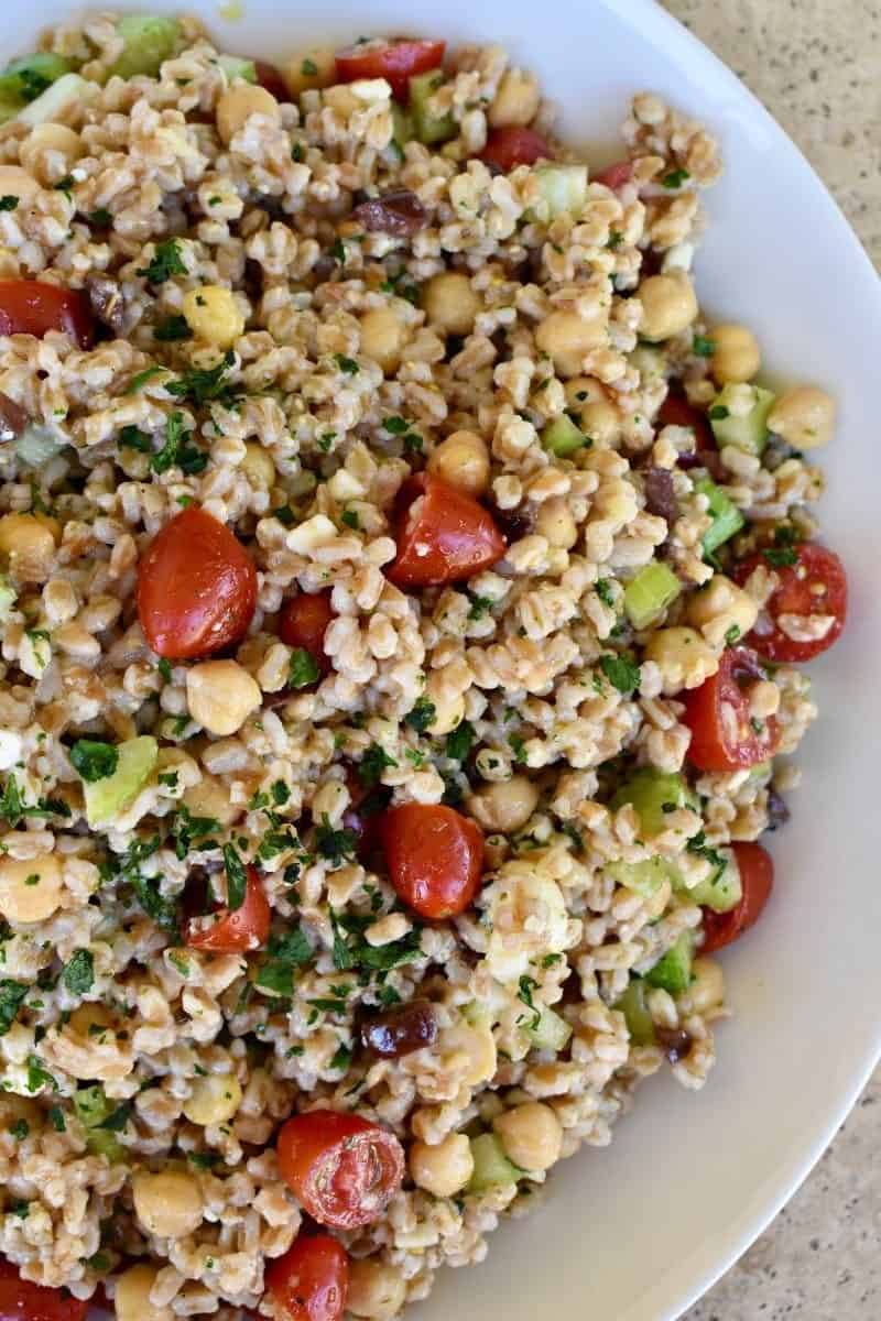 Farro Salad Recipe in a white bowl with tomatoes, feta, and cucumbers. 