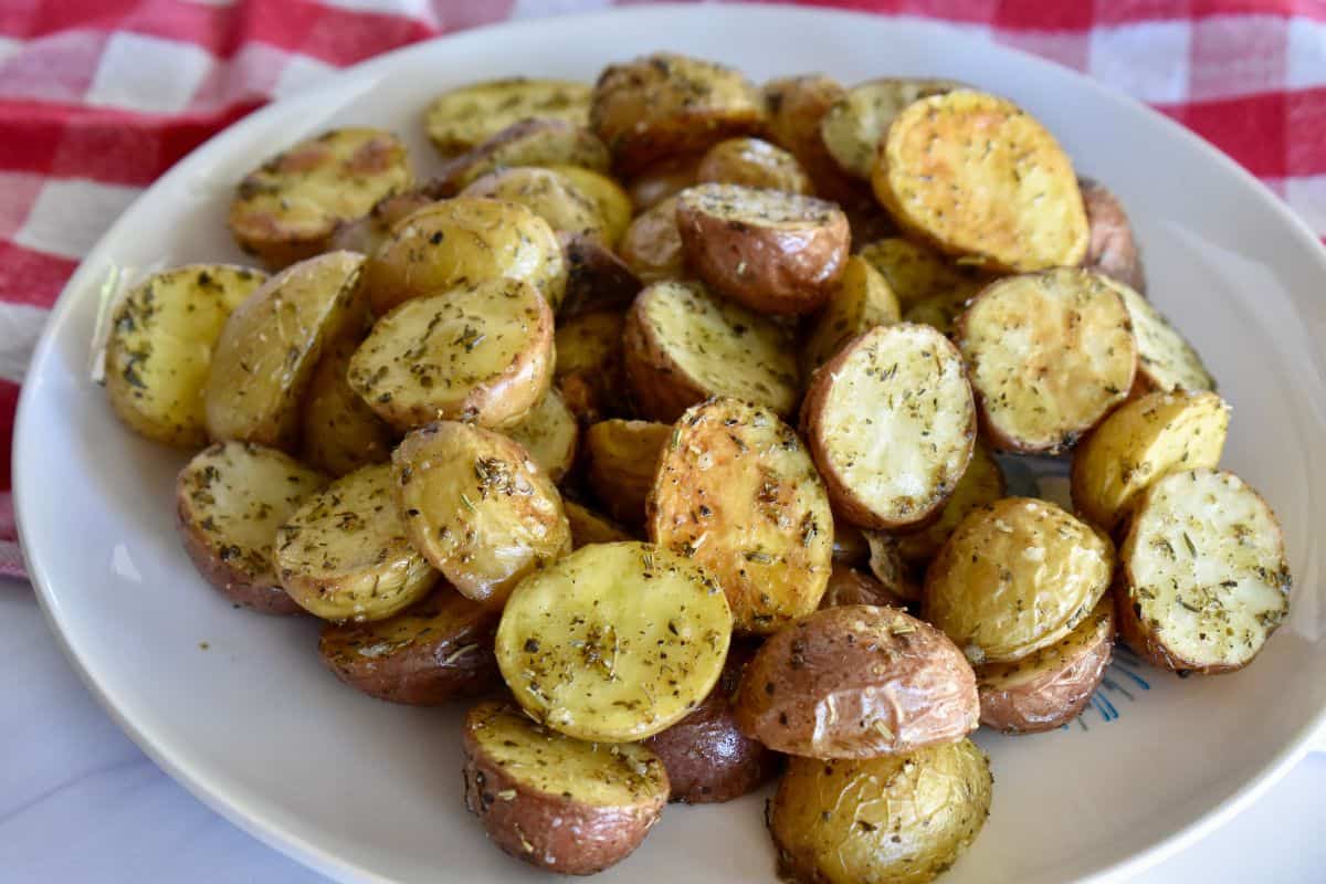 Italian Roasted Potatoes on a white plate with a checkered napkin in the background. 