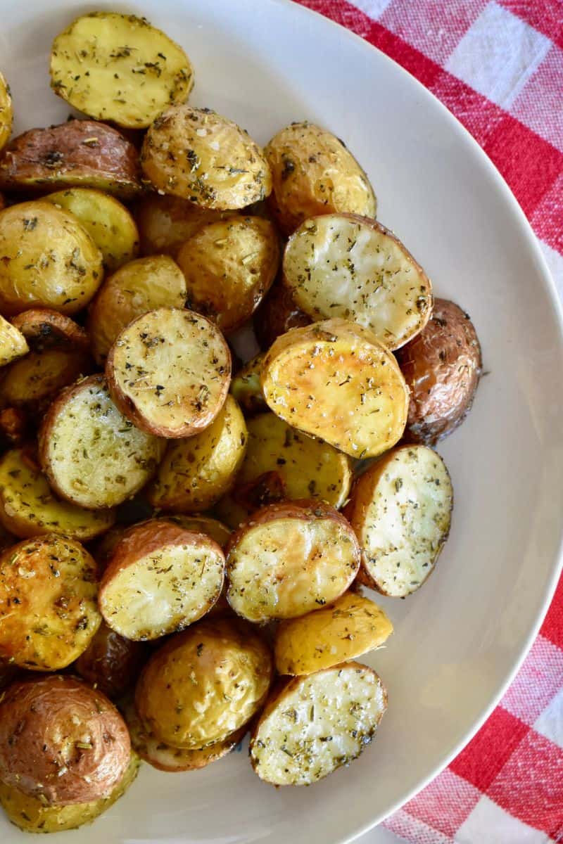 Italian Roasted potatoes in a white bowl on a red and white checkered napkin. 