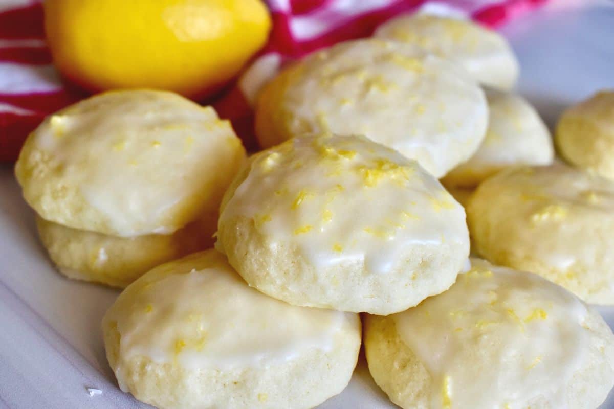 Lemon Ricotta Cookie recipe stacked on each other on a white countertop with a checkered napkin in the background. 