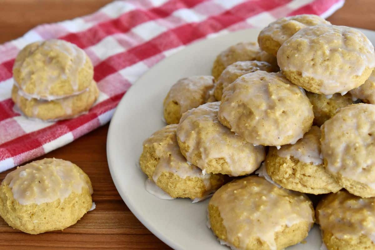 Pumpkin ricotta cookies piled on a plate with a checkered napkin in the background. 