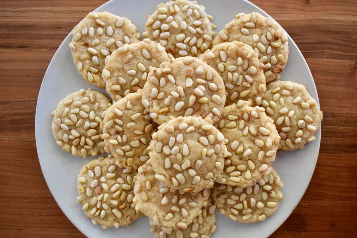 Overhead photo of pignoli cookies stacked on a plate. 