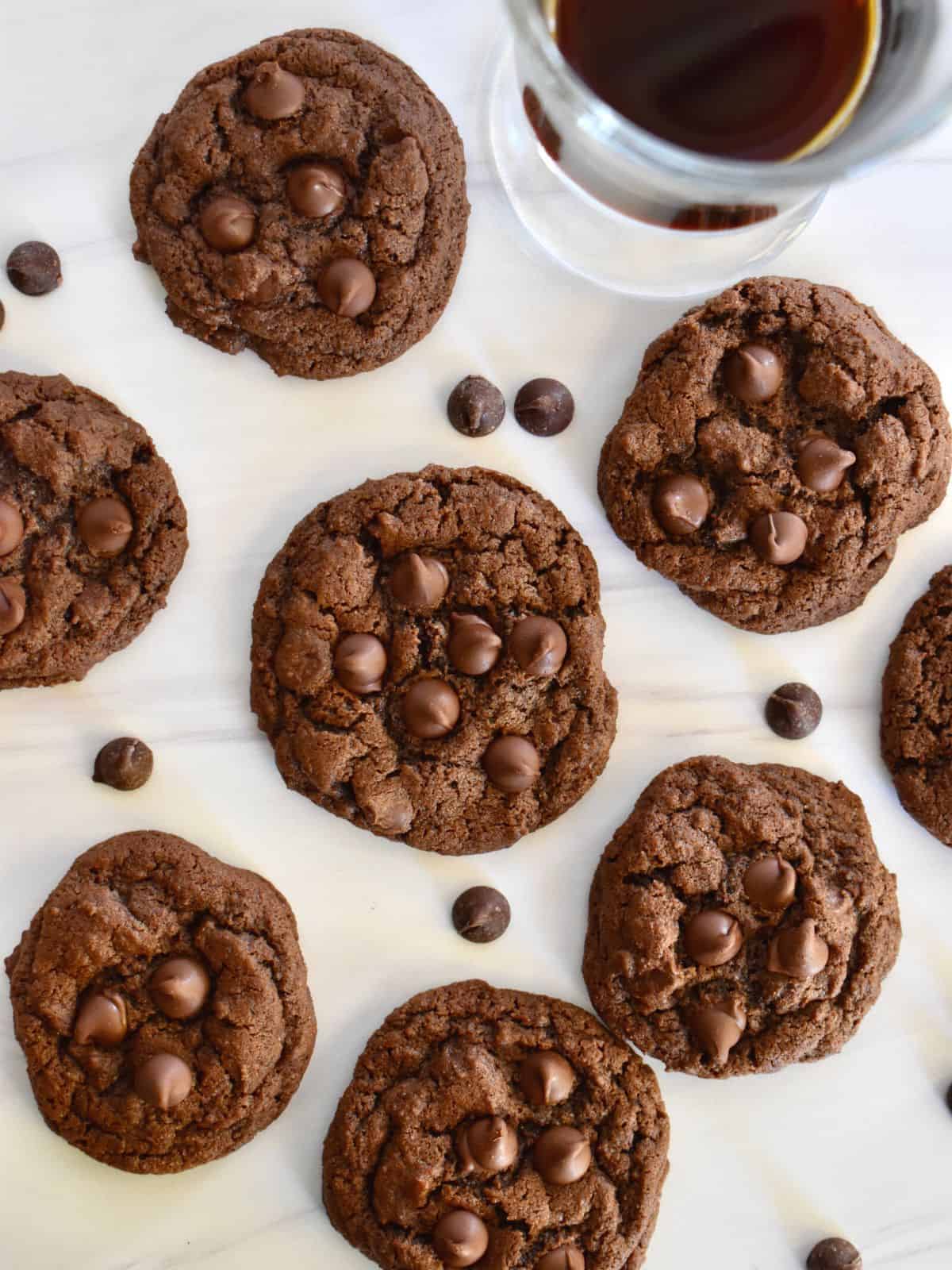 Chocolate Espresso Cookies overhead photo on a white countertop with chocolate chips and espresso beans scattered around. 