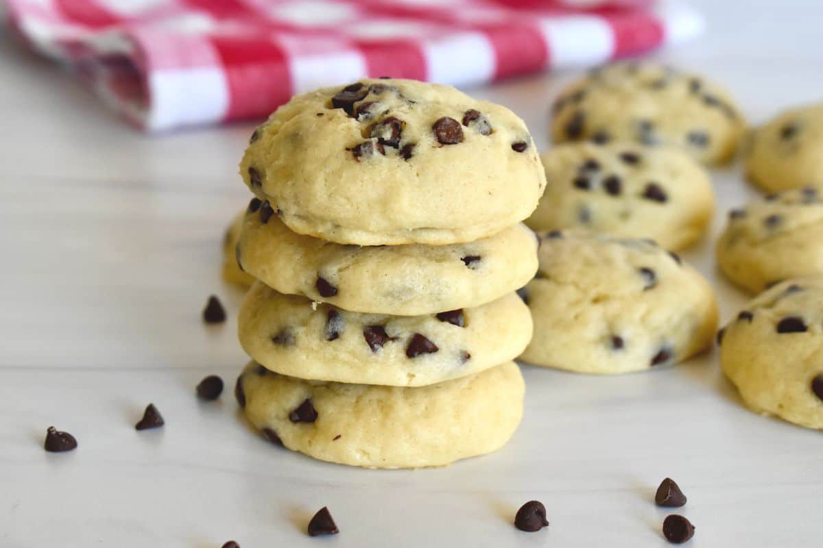Chocolate Chip Ricotta cookies stacked on each other on a countertop with a checkered napkin in the background. 