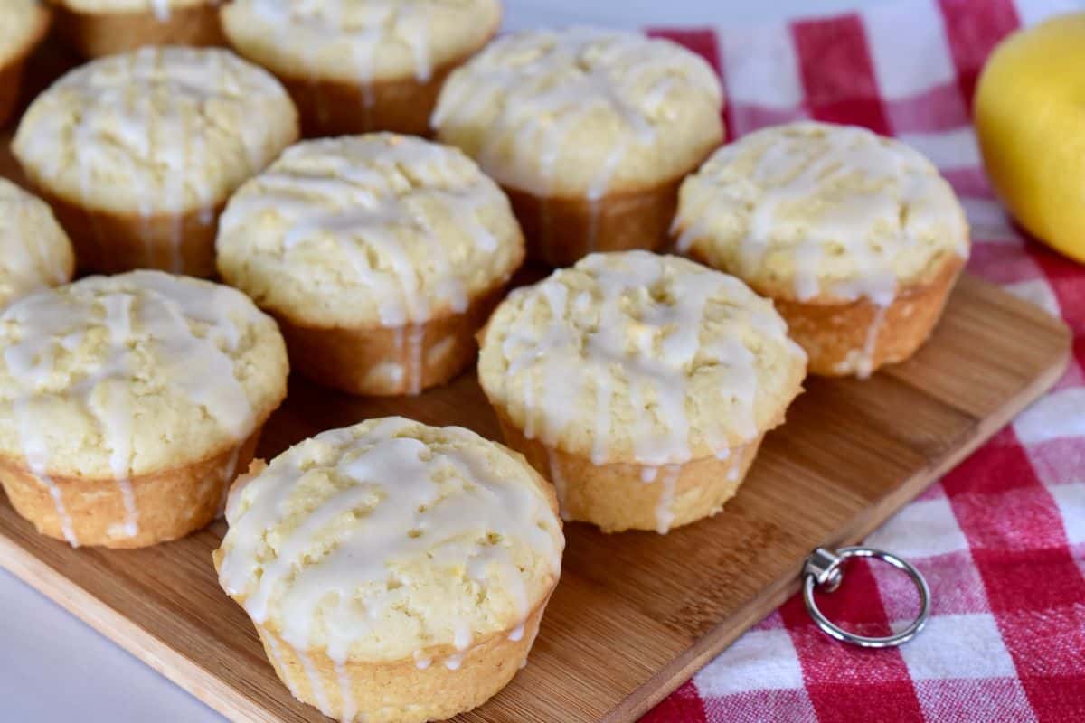 Lemon Ricotta Muffins on a wooden board with a lemon in the background.