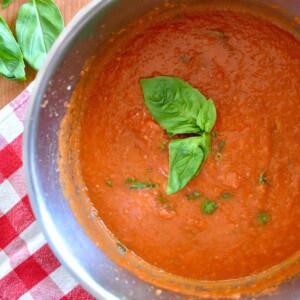 Sugo in a pot with a basil leave on top.