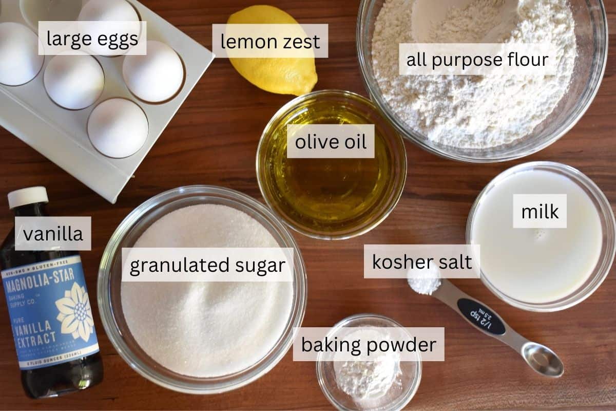 overhead photo of recipe ingredients including olive oil, flour, lemon sugar, eggs, baking powder, salt and vanilla.