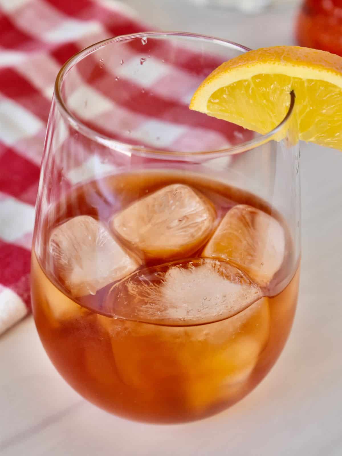 Aperol Negroni in a glass with ice and a lemon wedge. 